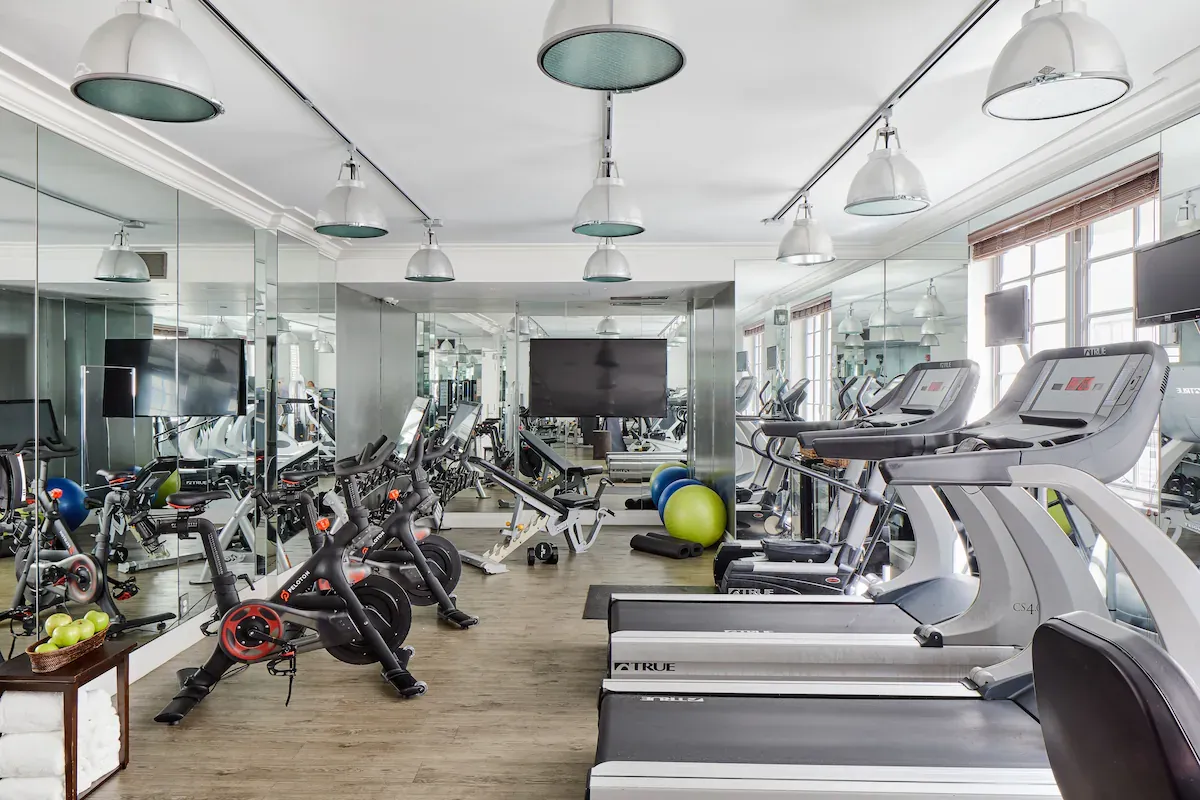 Fitness center at The Betsy Hotel in South Beach with treadmills, spin bikes, strength equipment, and mirrored studio space for wellness-focused travelers.
