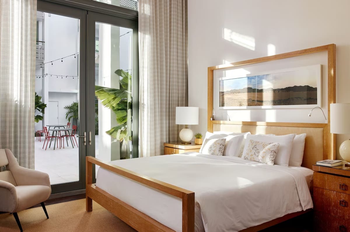 Bright guest room at The Betsy Hotel in South Beach with courtyard terrace access, showcasing calm boutique luxury and high-quality bedding for first-time visitors.