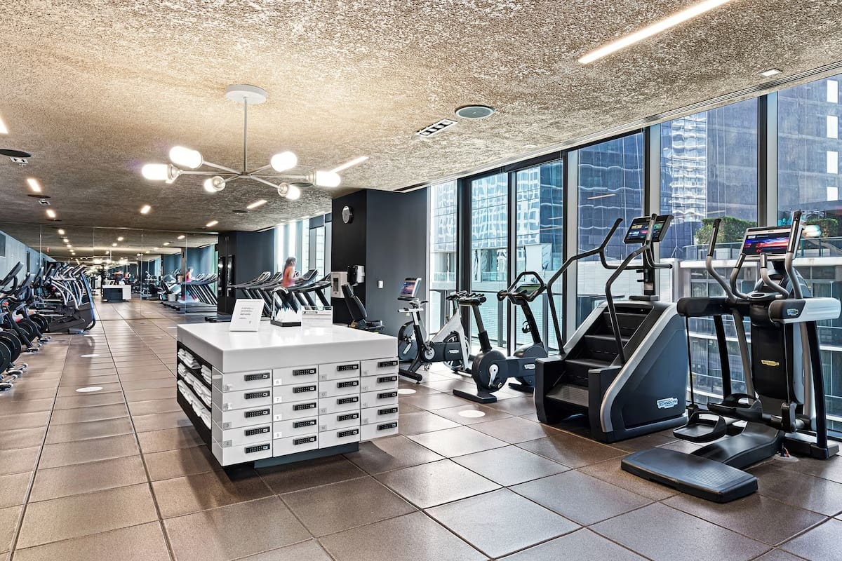 24-hour fitness center at EAST Miami in Brickell with cardio machines, strength equipment, and floor-to-ceiling windows overlooking downtown Miami.
