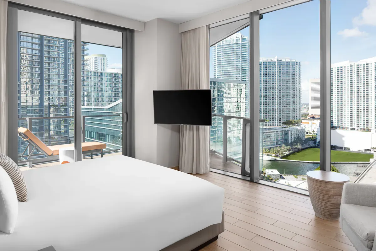 Modern luxury bedroom suite at EAST Miami in Brickell with floor-to-ceiling windows, private balcony, and skyline views over downtown Miami.