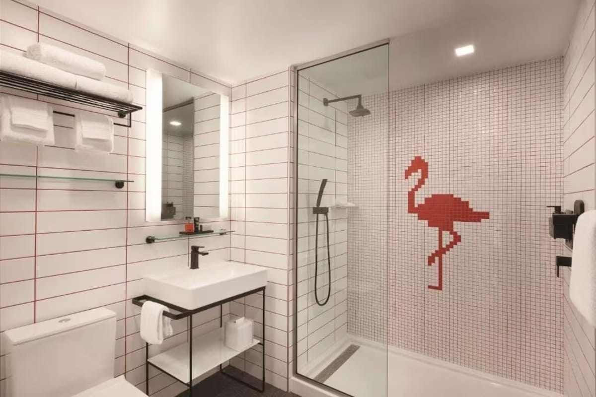 Modern bathroom at Kompose Boutique Hotel Miami Airport featuring walk-in shower with pink flamingo tile design