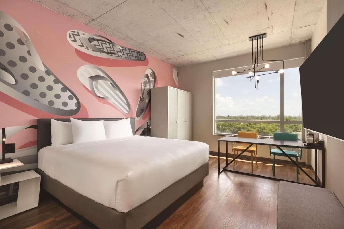 Modern guest room at Kompose Boutique Hotel Miami Airport with artistic accent wall and floor-to-ceiling windows.