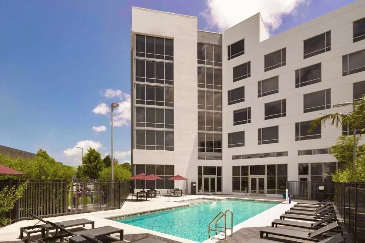 Outdoor swimming pool at Kompose Boutique Hotel Miami Airport with lounge chairs and courtyard setting