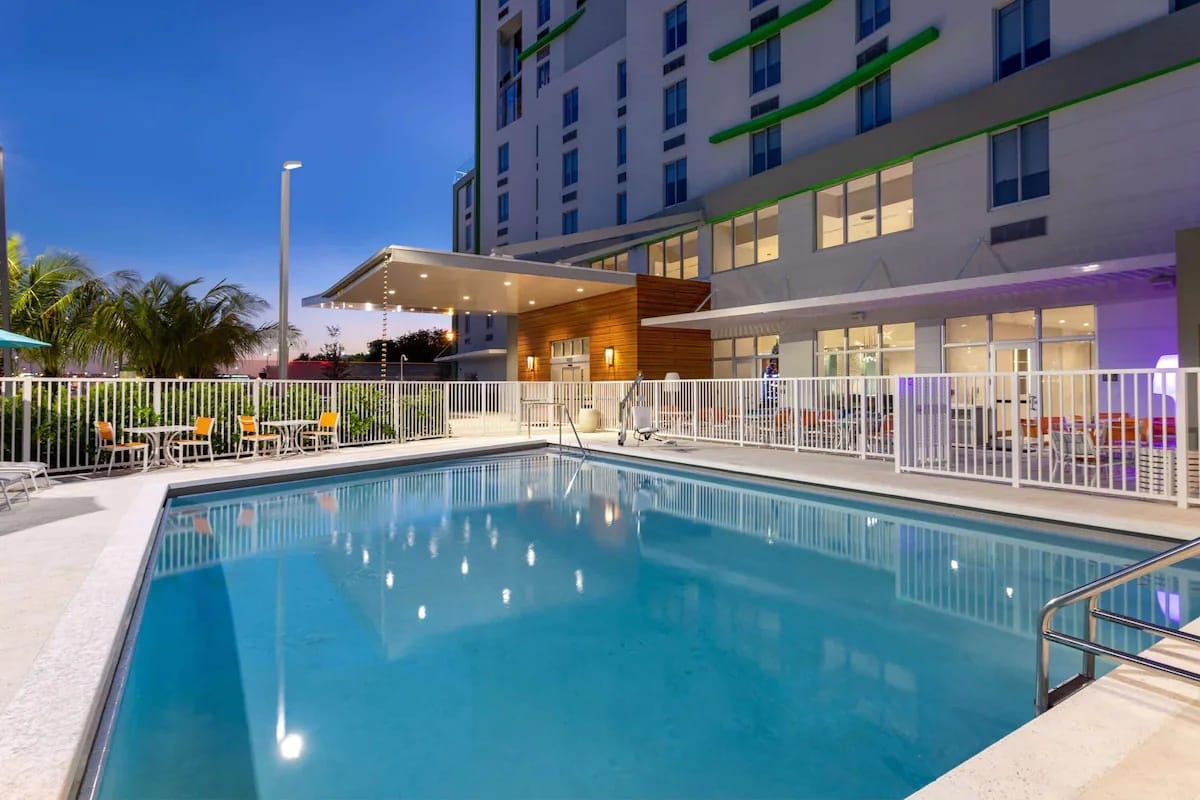 Outdoor swimming pool at Wyndham Garden Miami International Airport with seating and lighting for overnight stays.