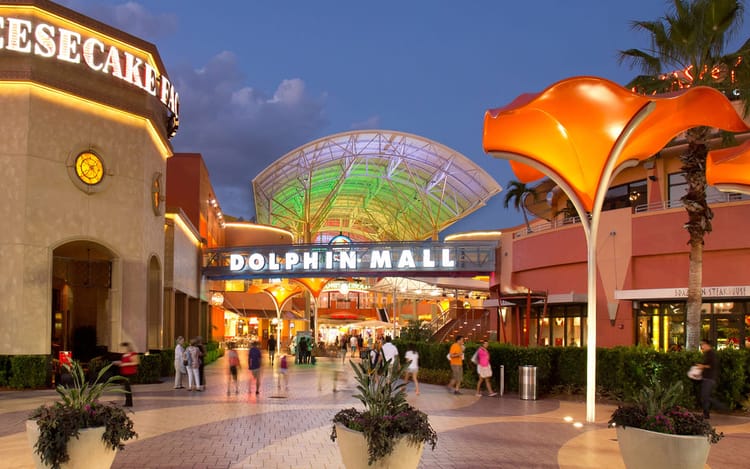 Main entrance plaza at Dolphin Mall in Doral, Miami with shops and evening lights